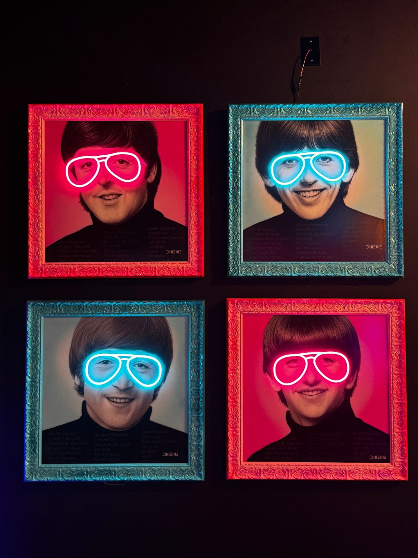 A four-piece neon wall art set featuring The Beatles, each framed in pink and blue ornate frames, with glowing neon LED glasses, created by Lux Neon x MJ Pop.